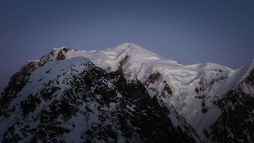 Timelapse of a spectacular sunrise casting a pink alpenglow on a majestic snow-capped mountain