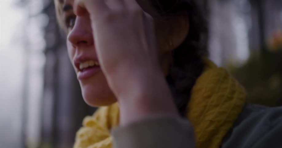 A slow-motion close-up pans up to reveal a young woman's face, filled with wonder and a smile as she takes in the forest