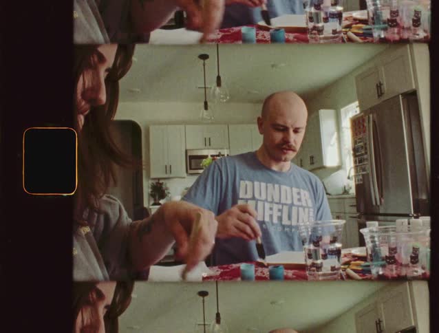 Vintage-style split-screen footage captures a man and woman painting together at a kitchen table
