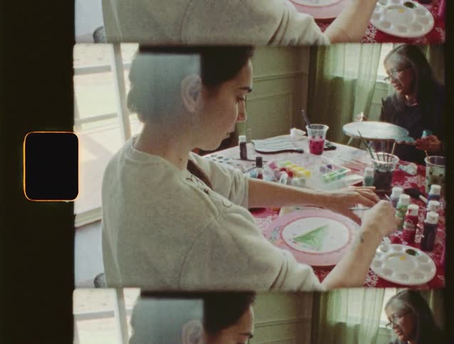 Authentic vintage film captures a family sitting at a table painting Christmas crafts together