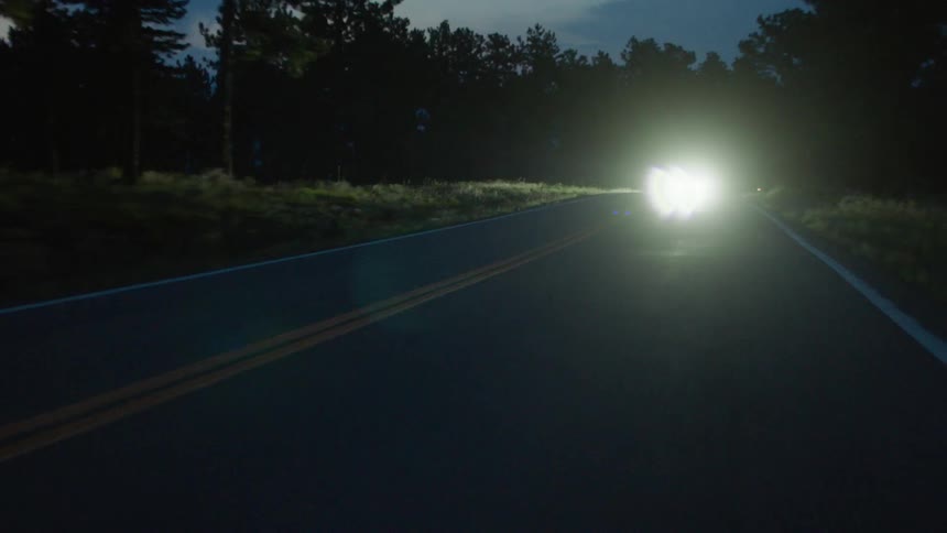 Cars have bright headlights on this dark road