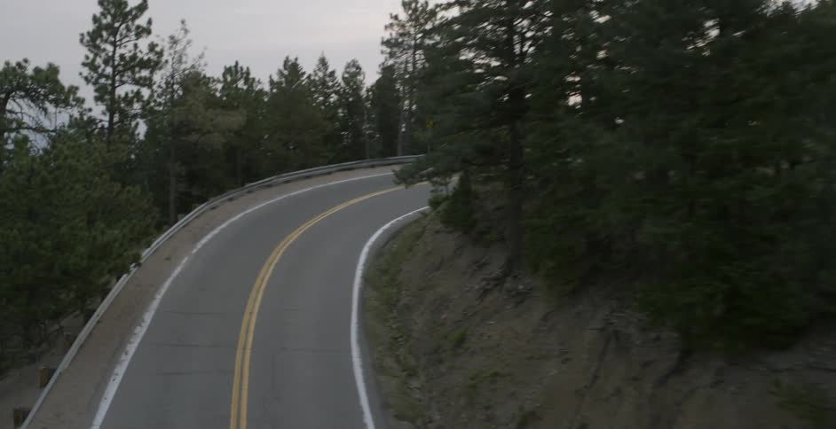 A white car passes on the road around a turn