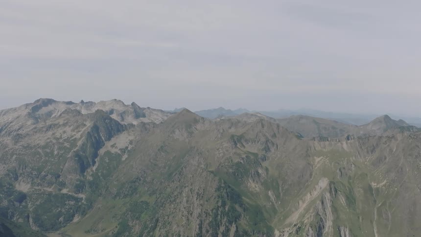 A serene, static view of a majestic mountain range stretching into the horizon under a hazy sky