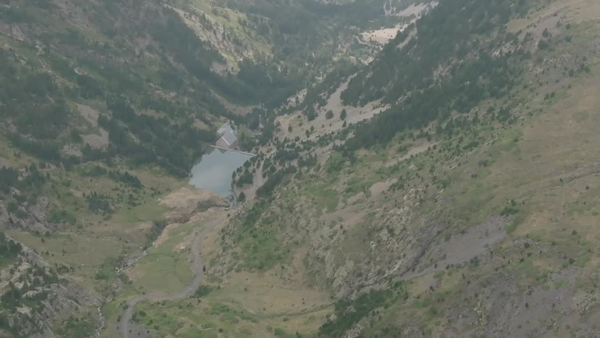 An aerial view captures the still waters of a secluded reservoir nestled deep within a vast, rugged mountain valley