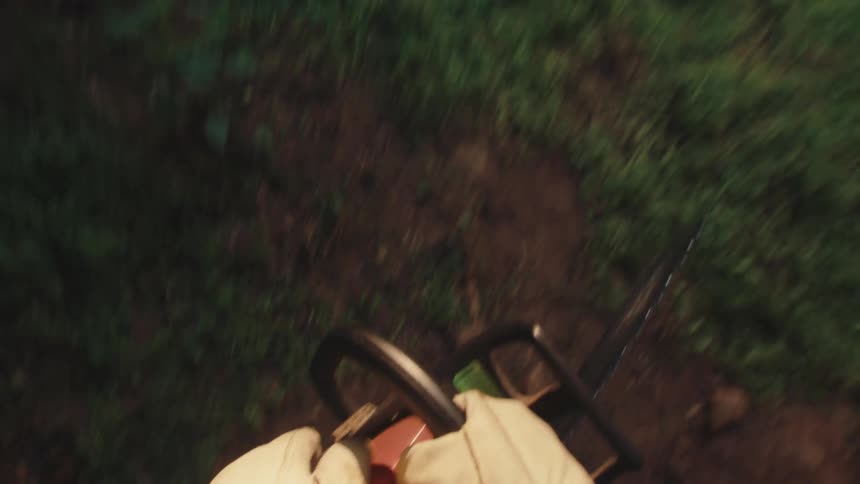 A first-person view of a person picking up a chainsaw at night and walking into a sunlit, grassy field