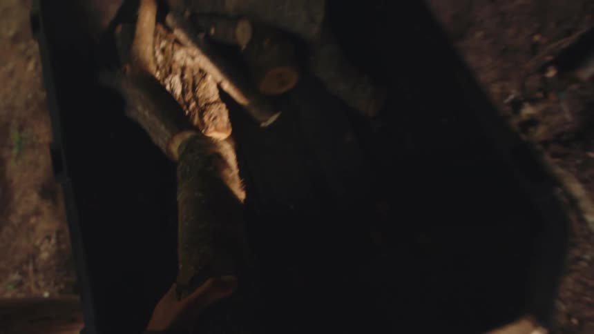 A first-person point of view of a person stacking firewood logs inside a rustic wooden cabin