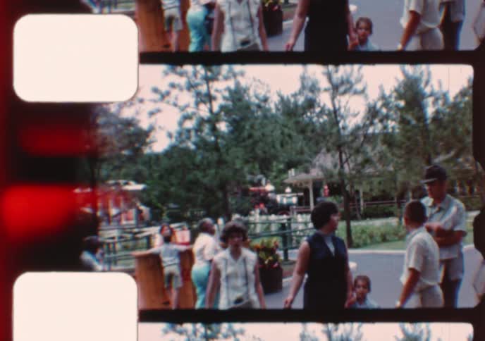 Vintage 8mm home movie footage shows families walking through an amusement park in the 1960s