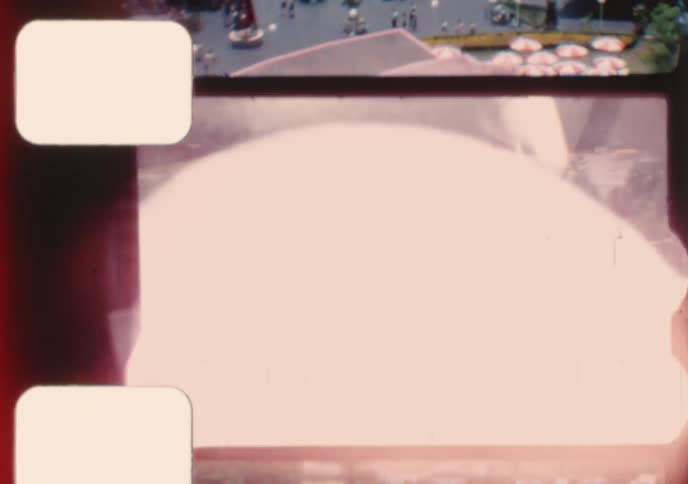 A high-angle point-of-view from a ride showcases various attractions at a vintage amusement park on a summer day