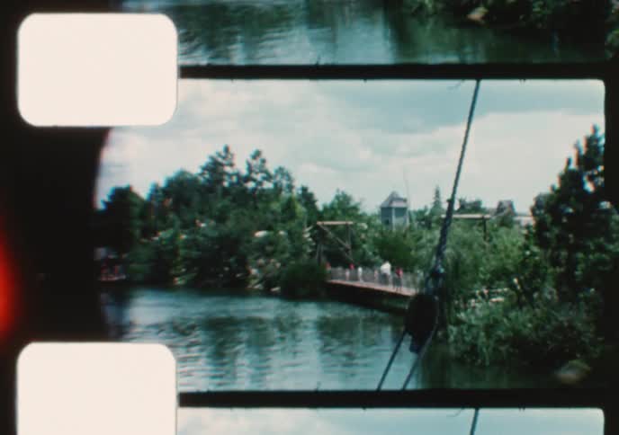 Vintage 8mm film captures the scenic view from a riverboat ride through a lush, adventure-themed amusement park