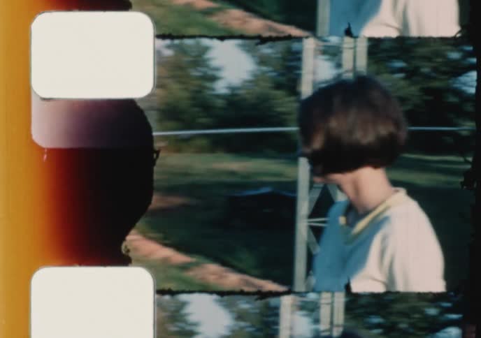 A happy young woman plays fetch with her energetic dog in a sunny backyard in this charming vintage 8mm home movie