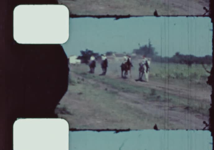 Authentic vintage 8mm film from Brazil captures a group of gauchos racing horses on a dirt road through the countryside