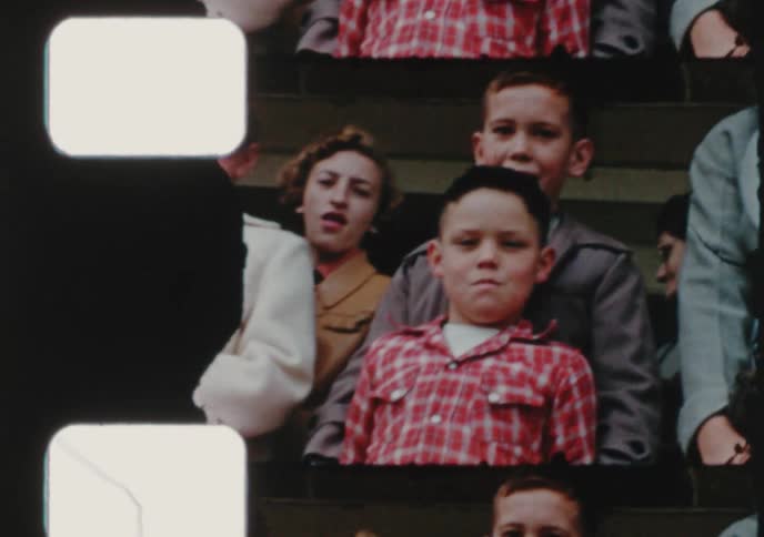 A vintage film strip pans across a large group of children and adults posing for a photo in the 1950s