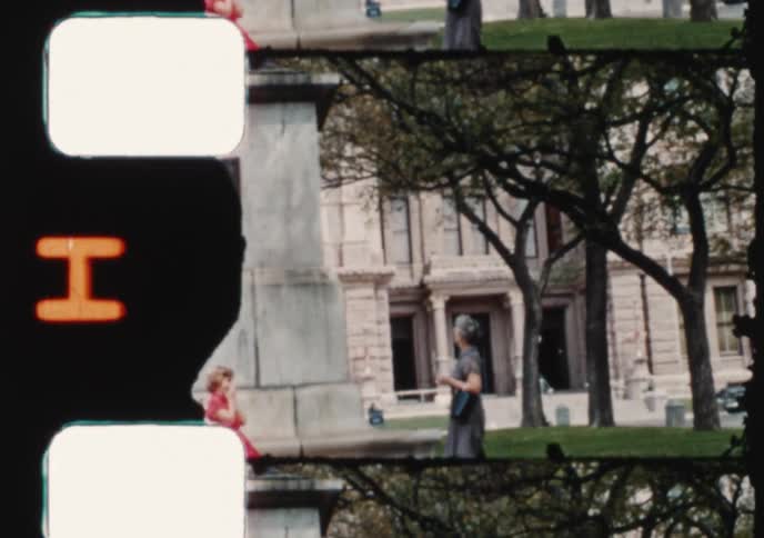 Vintage 16mm film captures scenes of a family admiring historical statues in a city park in the 1950s