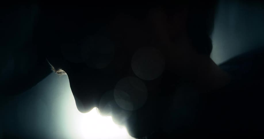 Intense close-up silhouette of a man screaming in slow motion against a bright light