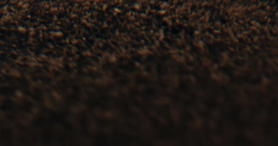 An extreme macro close-up of brown powder particles vibrating and dancing in slow motion