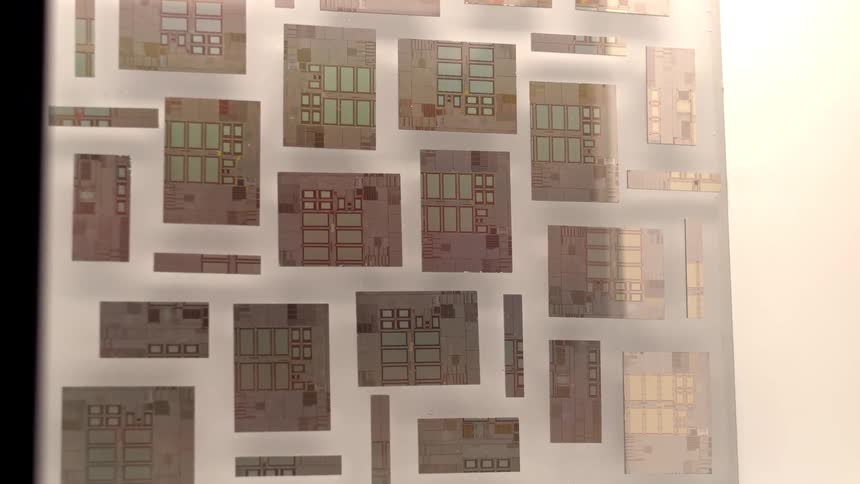 A slow zoom-in on a technical display of various computer microchips and integrated circuit dies against a bright white background