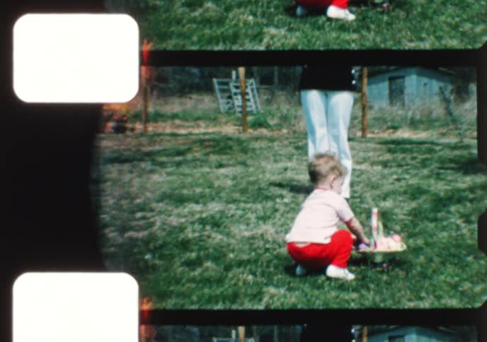 A cute toddler enjoys an Easter egg hunt in the backyard with his mom in this authentic vintage home movie from the 1970s