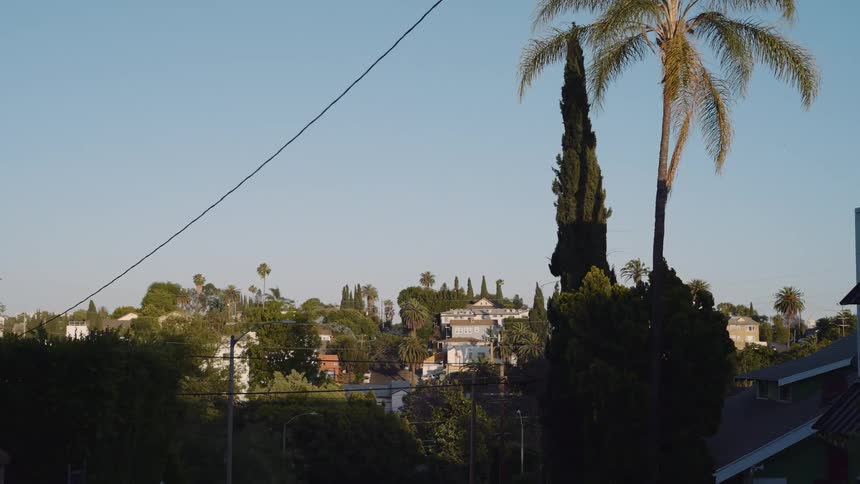 A slow pan reveals a quiet hillside neighborhood bathed in the warm light of a sunny day
