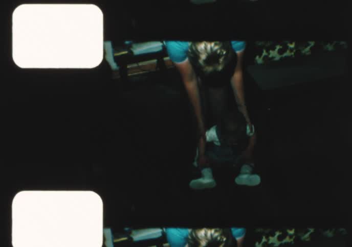 Authentic 8mm home movie from the 1970s shows a mother helping her baby son take his first steps in the living room