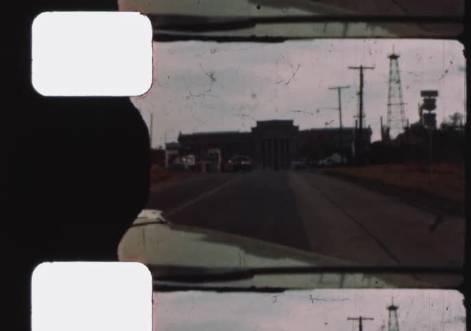 An archival 8mm film clip shows a drive toward the Oklahoma State Capitol Building, with an oil derrick on the grounds, circa 1955