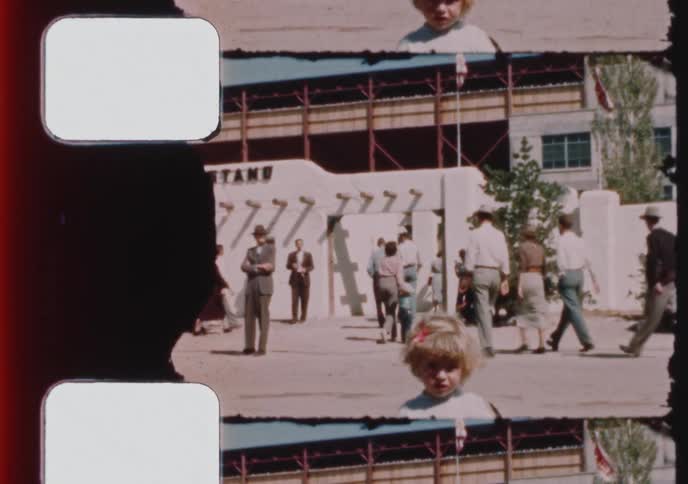 Vintage 8mm film captures families and crowds enjoying a sunny day at a grandstand with Southwestern adobe architecture in the 1950s