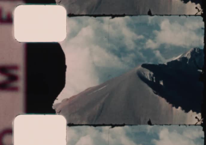 Vintage 8mm film captures an aerial view of a majestic mountain range and a propeller plane engine while in flight