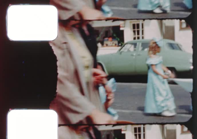 A classic American small town parade from the 1950s featuring children in costumes, flowers, and an American flag