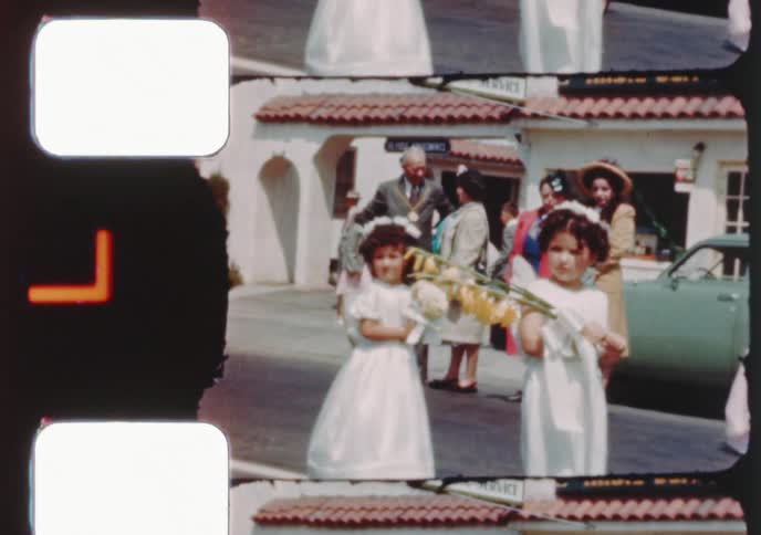 Vintage 16mm film captures children in white gowns and altar boy robes participating in a small town religious parade