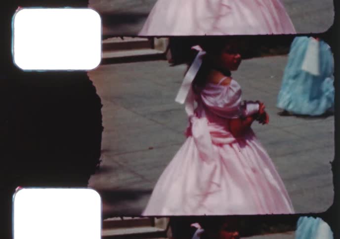 Children dressed in elaborate, old-fashioned costumes for a parade or festival pose for the camera in this vintage 8mm film from the 1950s