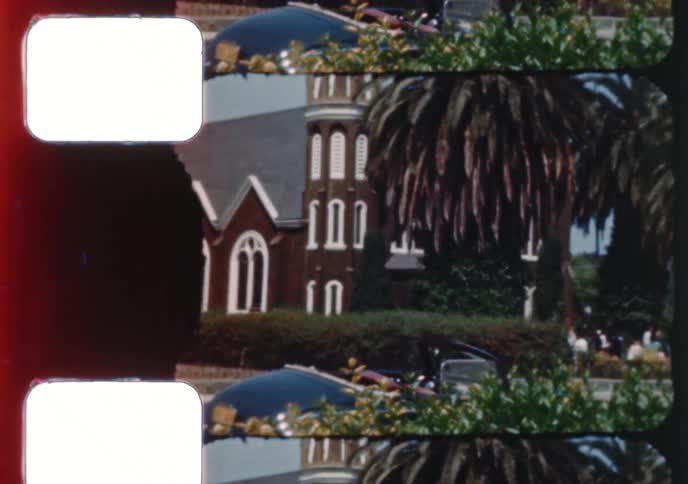 A vintage 8mm film strip develops to reveal scenes of a historic church and a procession with people in period dress