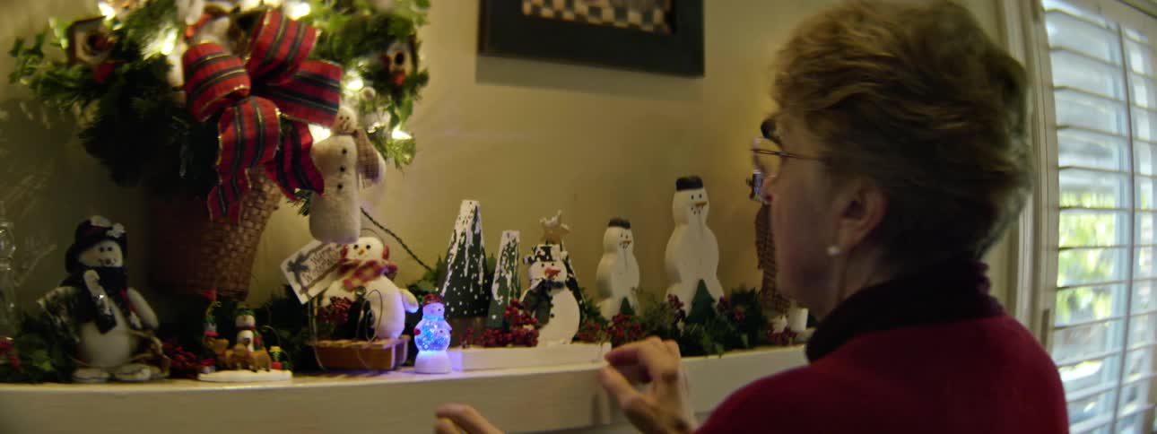A woman arranges christmas decorations on the mantel