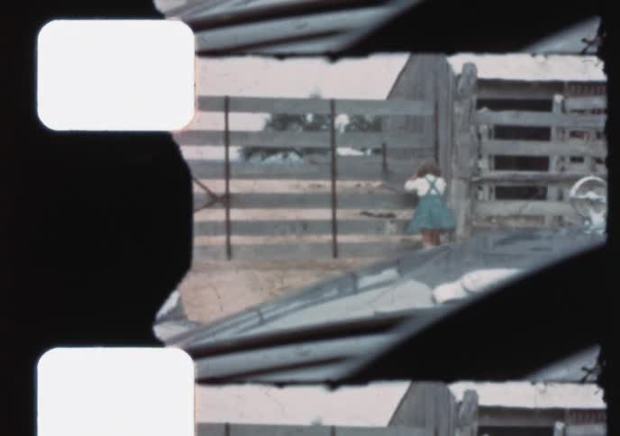 Vintage film captures a young boy and girl playing happily on a rustic farm in the 1950s