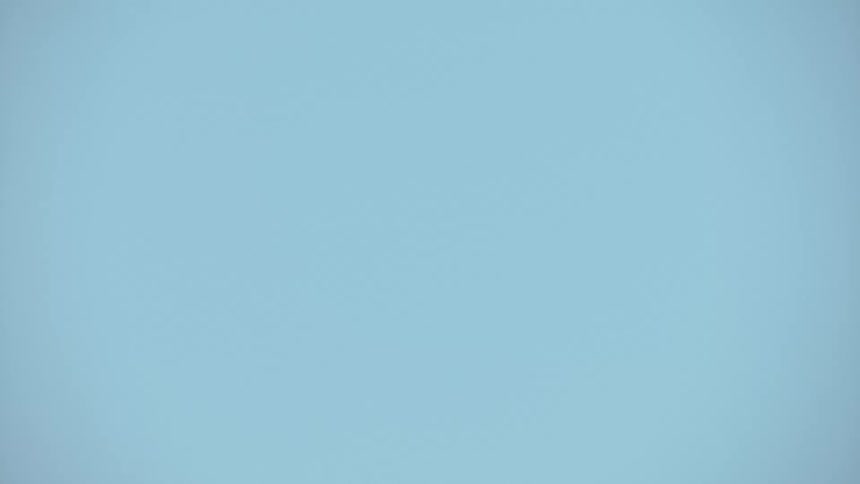 An F-22 Raptor fighter jet performs a spectacular high-G climb in super slow motion, creating vapor trails across its wings against a clear blue sky
