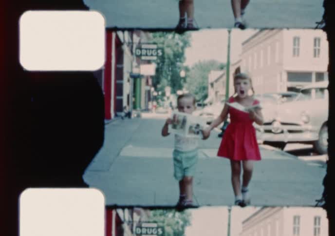 Vintage 8mm footage shows a young brother and sister happily walking down Main Street with comic books before she gives him a kiss on the cheek