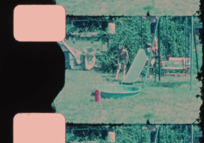 Vintage home movie of children playing on a backyard slide and splashing in a small wading pool
