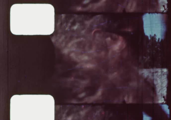 Vintage 16mm film strip scan shows a man smoking and running his hands through his hair, followed by a shot of a smiling young boy