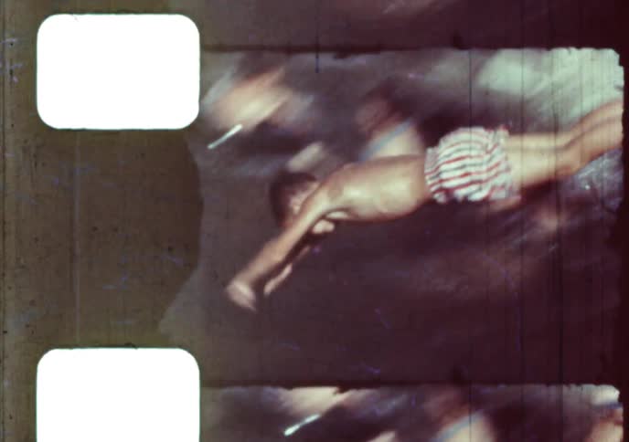 A young boy dives into a swimming pool to join his friends playing with inner tubes in this vintage home movie from the 1960s