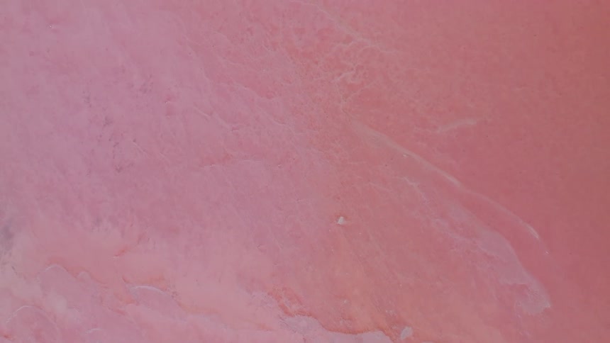Aerial top-down view of a surreal pink salt lake revealing its unique mineral patterns