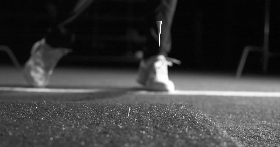 A dramatic black and white super slow-motion close-up of a golf driver hitting a ball off a tee at a driving range