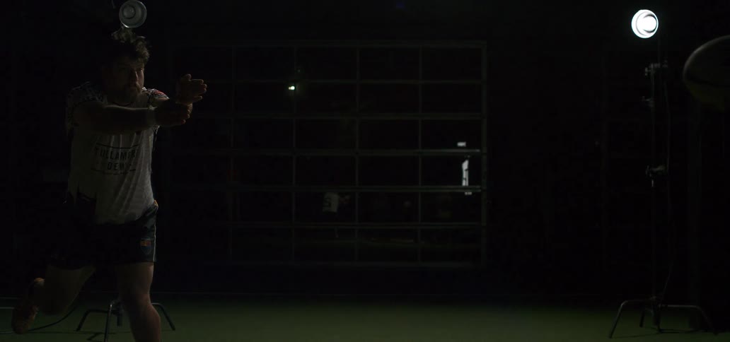 A rugby player executes a perfect pass in slow motion under dramatic studio lighting