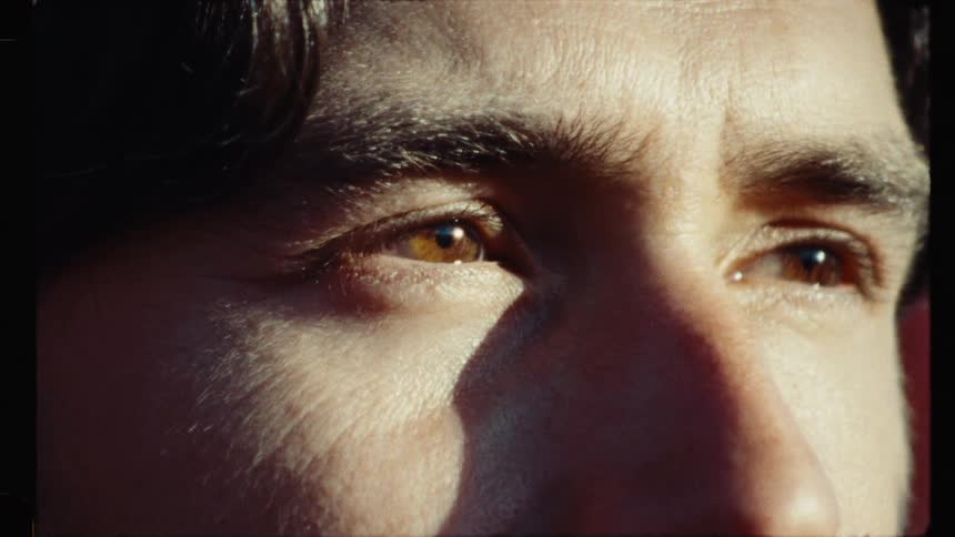 A nostalgic, grainy close-up of a man's contemplative eyes looking into the warm sunlight