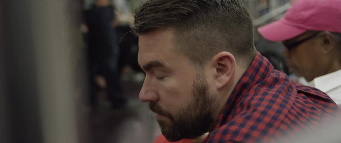 Close up of a bearded man sitting inside a subway car