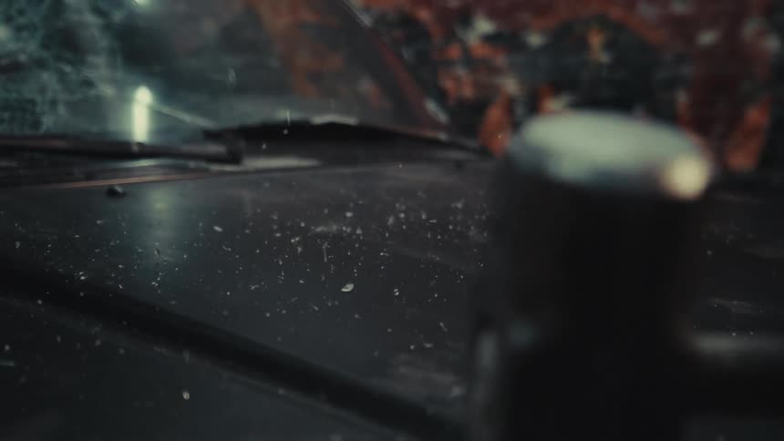 Slow motion close-up of a sledgehammer smashing into the hood of a black car, sending debris flying