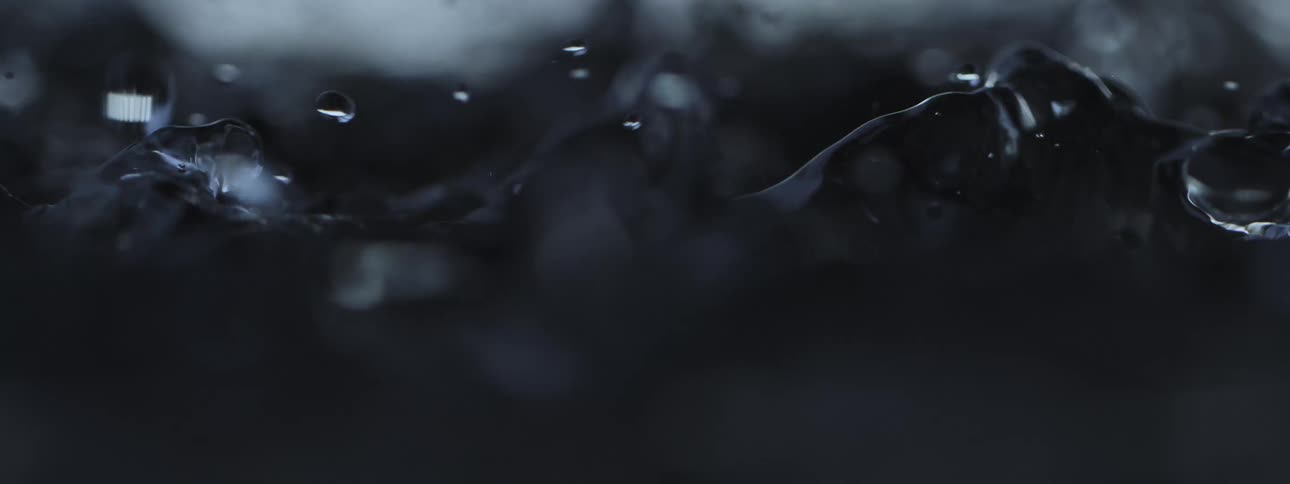 Dark, moody water ripples and splashes in an abstract slow-motion macro shot