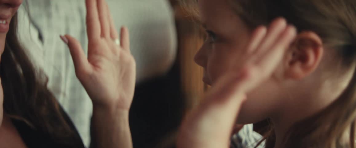 A loving mother and her young daughter share a tender moment, playing a gentle hand game together in a slow-motion close-up