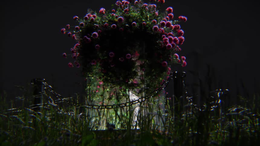 A somber tombstone adorned with a vibrant floral wreath sits in a dark, grassy cemetery at night
