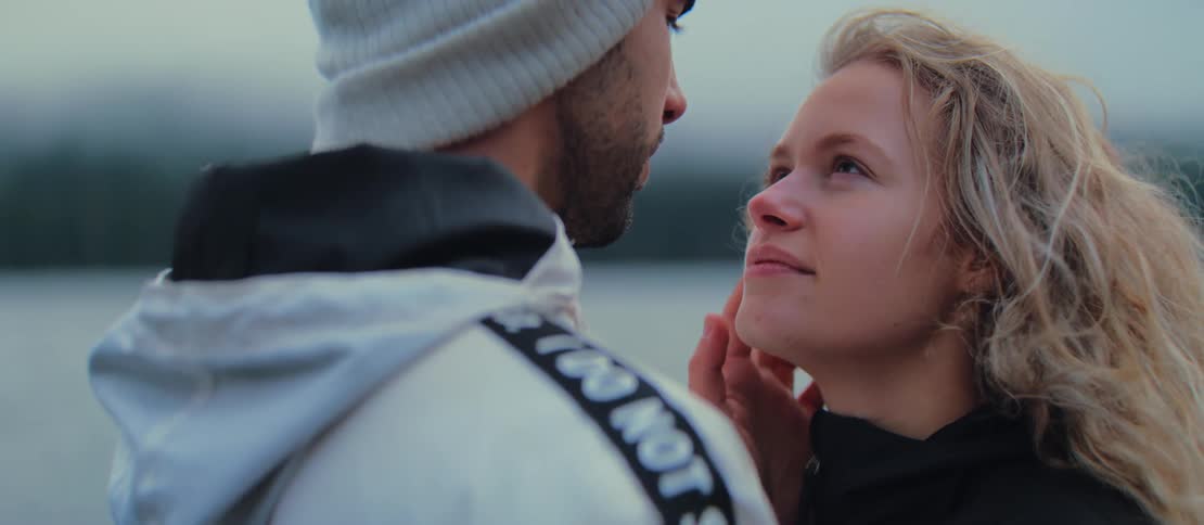 An affectionate couple shares a tender kiss in slow motion during an intimate outdoor moment