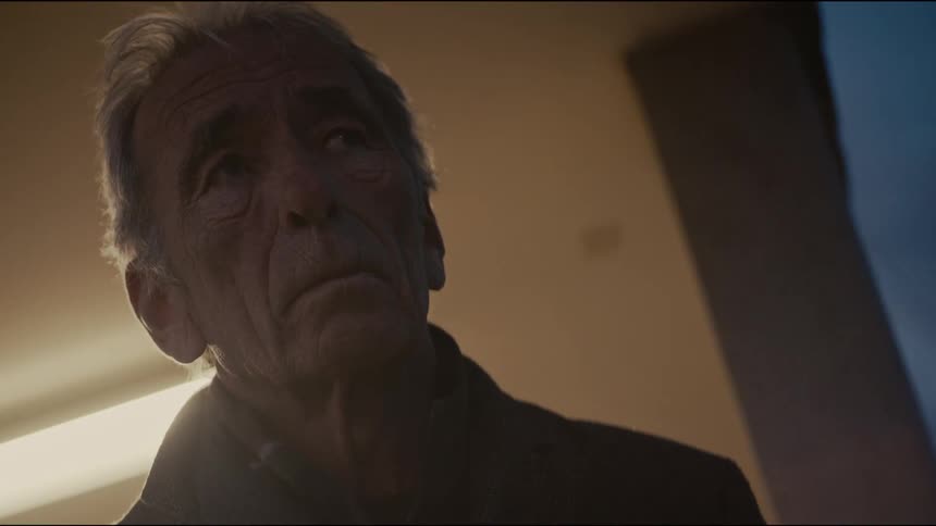 A dramatic low-angle close-up of a serious elderly man with a contemplative expression