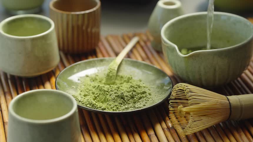 A traditional Japanese matcha tea ceremony in progress, from scooping the fine green powder to whisking it into a frothy, healthy beverage