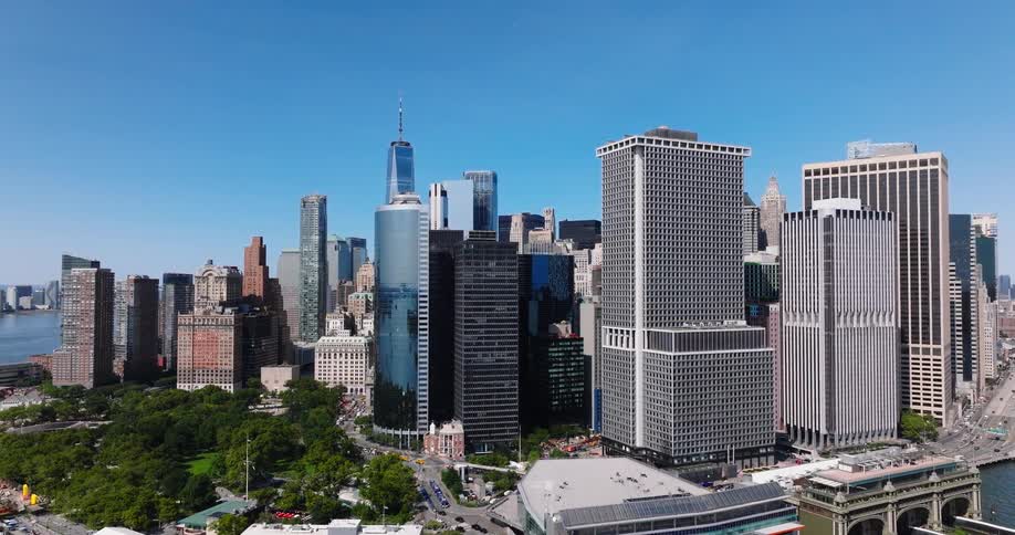 Slow aerial pull-back reveals the iconic Lower Manhattan skyline, Battery Park, and the Staten Island Ferry Terminal on a sunny day